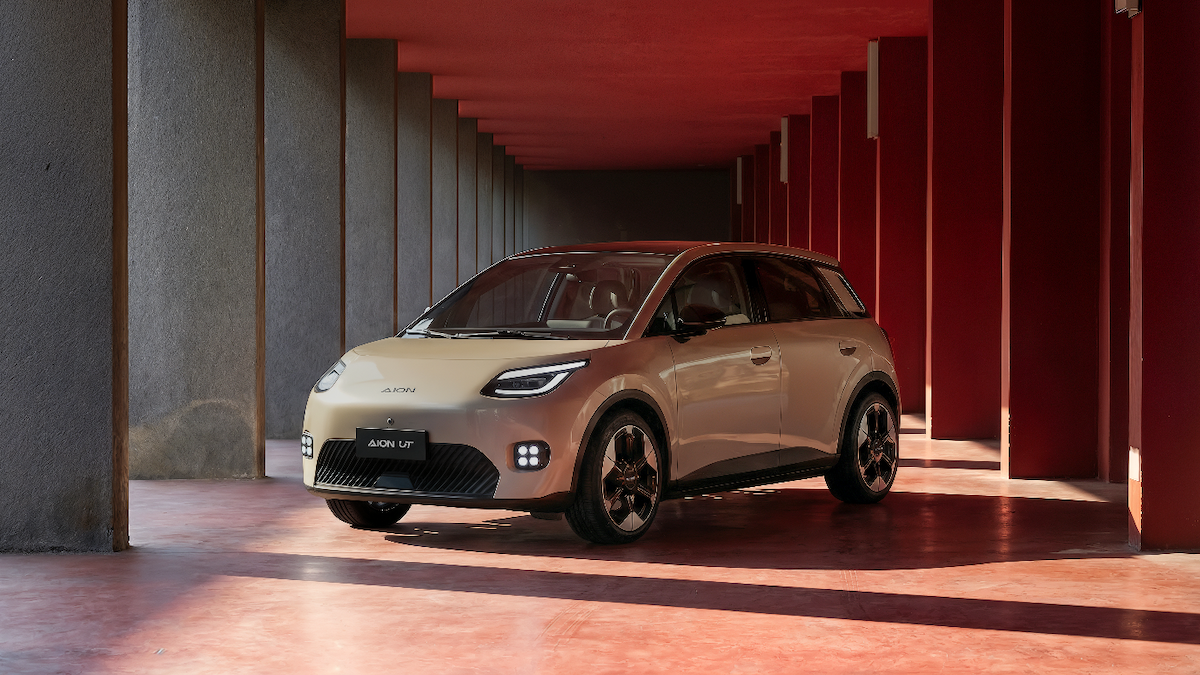 AION UT eletrico compacto estacionado num espaco moderno com iluminação vermelha, destacando o design aerodinâmico.