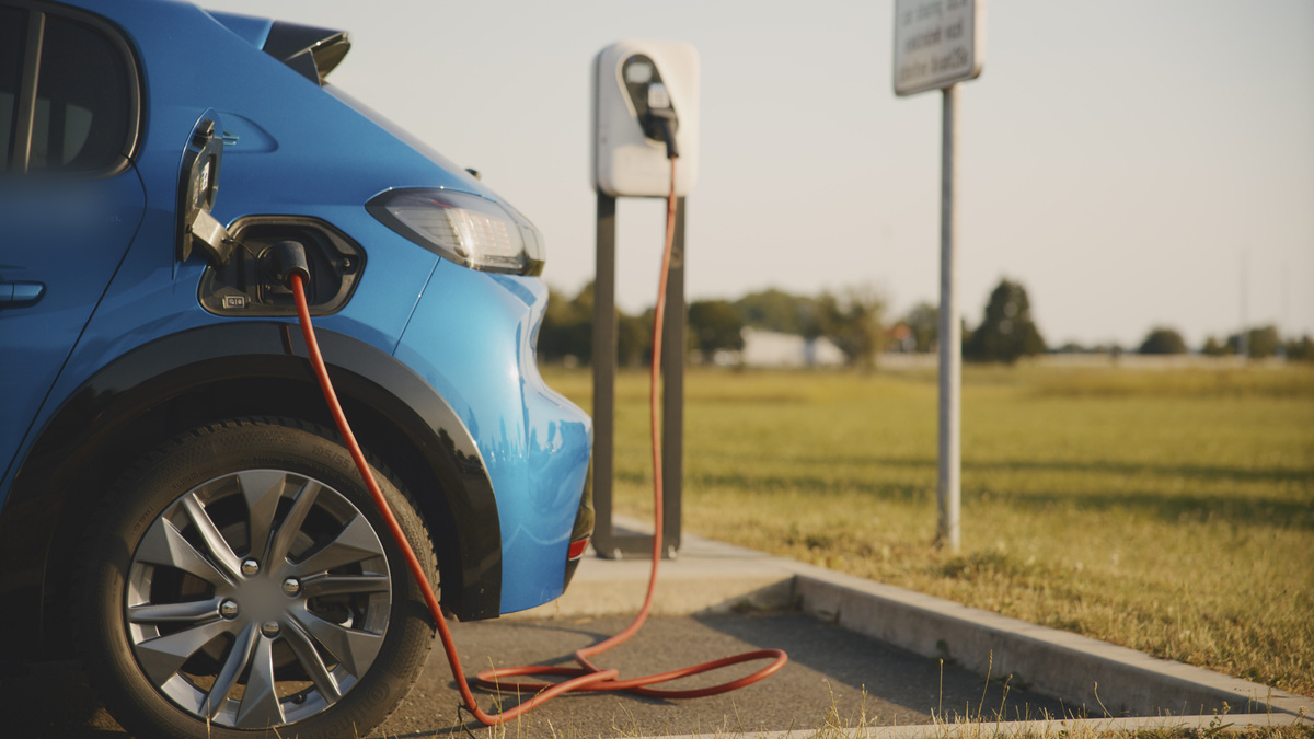 Carro elétrico em carregamento público, ilustrando o aumento da procura por veículos elétricos na Europa devido à subida dos preços dos combustíveis fósseis.
