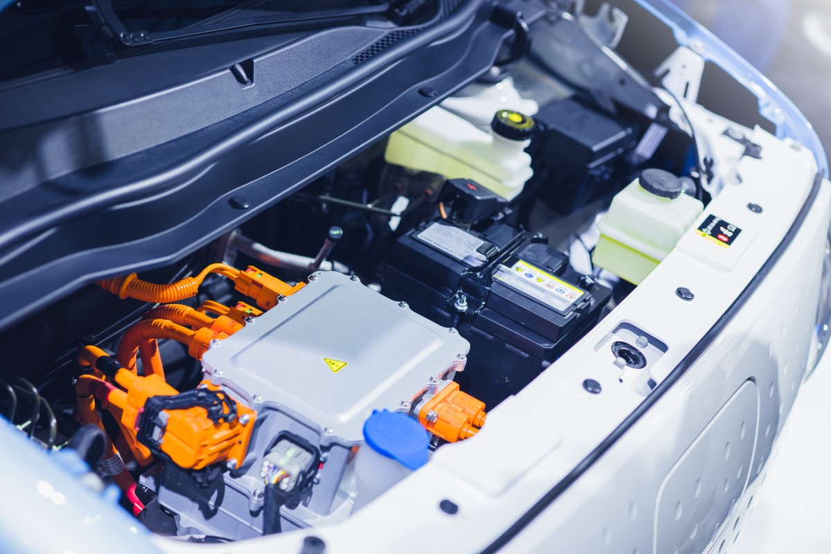 Técnico a realizar diagnóstico de bateria de alta voltagem num carro elétrico em oficina autorizada