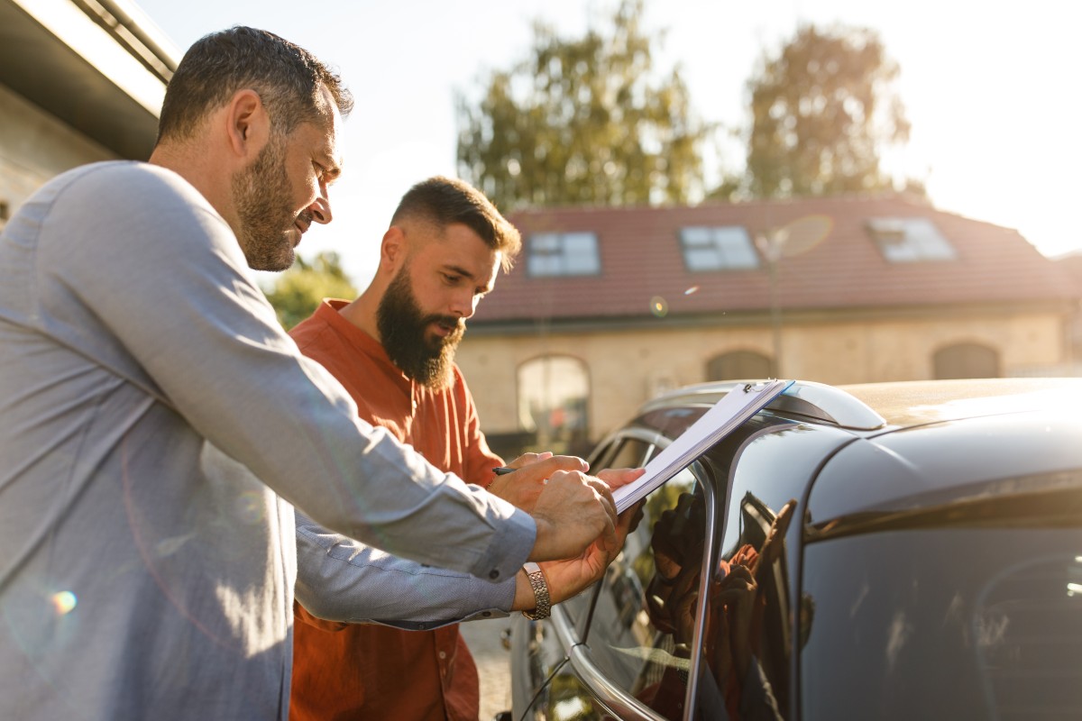Caderno de revisões de um automóvel com carimbos de concessionária oficial, sobre o capot do carro