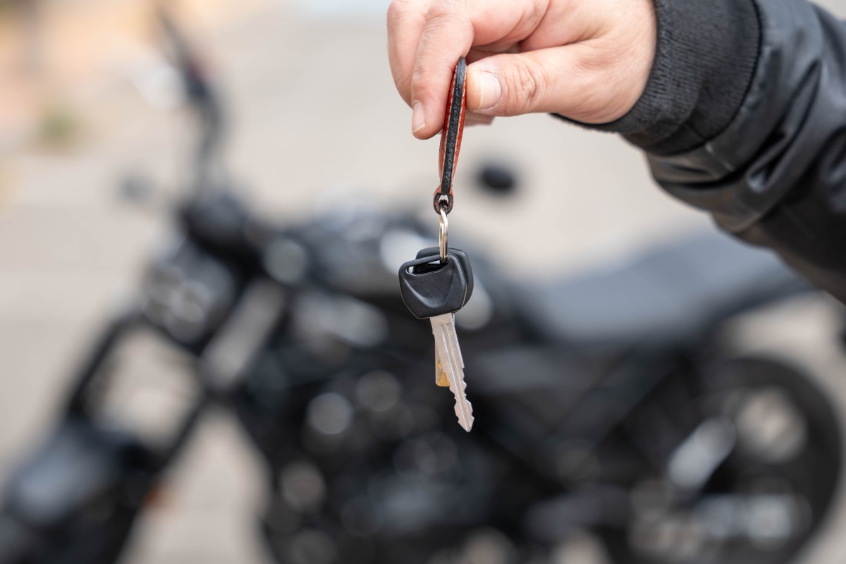 Pessoa a comparar anúncios de carros usados num computador portátil, com tabelas de preços visíveis no ecrã, num ambiente doméstico