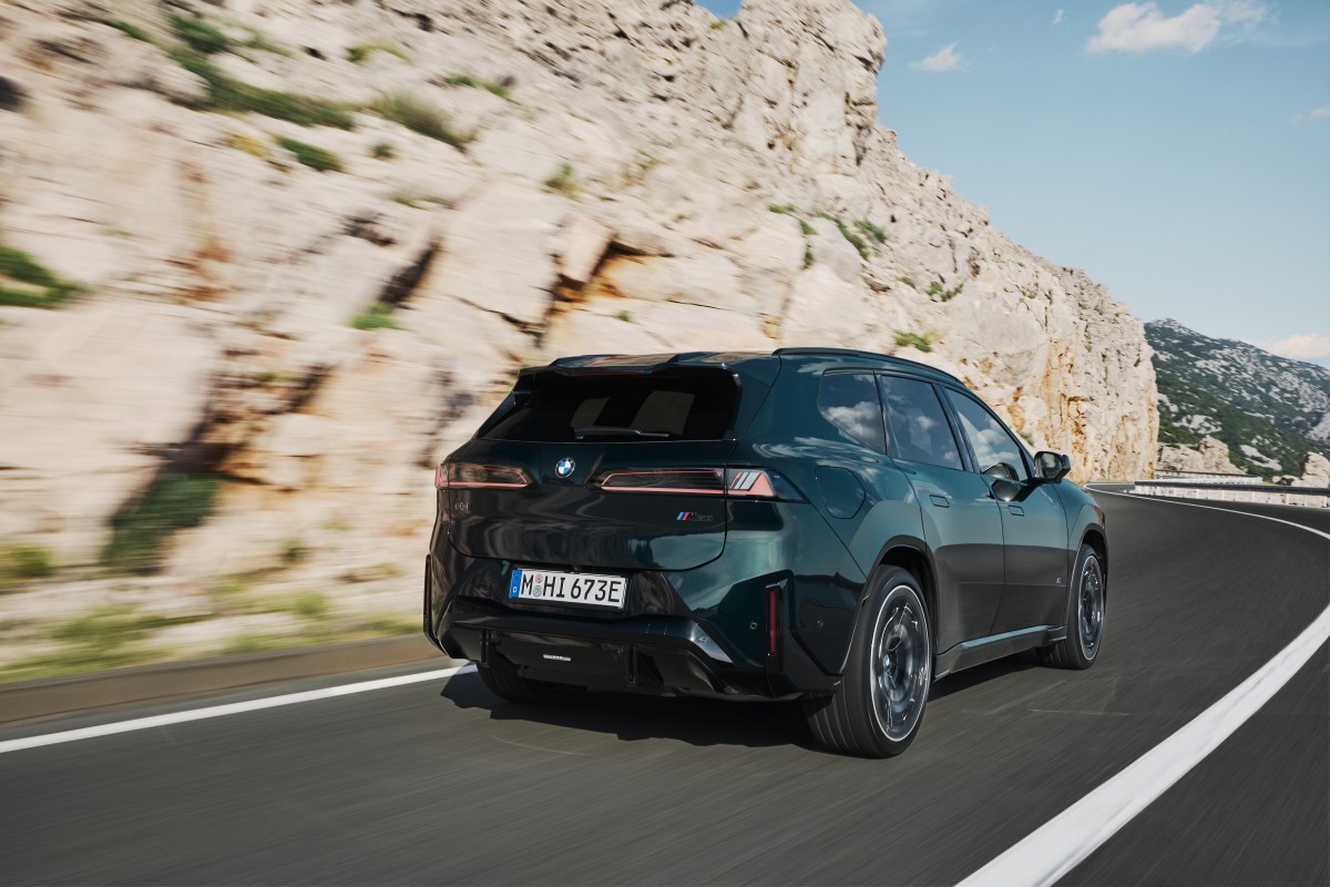 BMW iX3 M em movimento numa curva de estrada, destacando a dinâmica de condução do SUV eléctrico